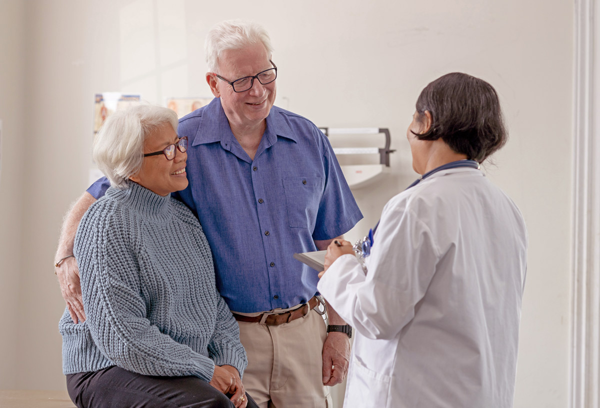 A friendly retired couple discuss a treatment plan with a doctor.